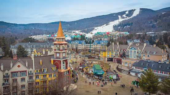 Aerial view of Mont Tremblant Ski Resort in winter, pedestrian village, clock tower, gondola and ski trail in the Laurentian Mountains of Quebec, Canada. Photo taking in December 2023.