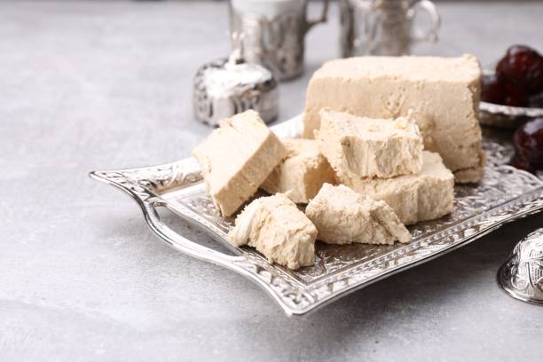 istock Pieces of tasty halva served on light grey table, closeup. Space for text 1920851235
