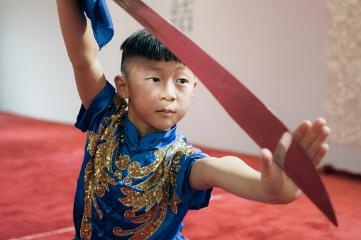 Young Chinese boy practising Wushu with a sword