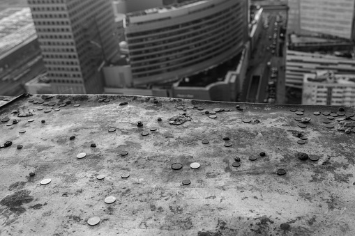 Coins resting on a ledge where tourists have tried to throw pennies off of a tall building