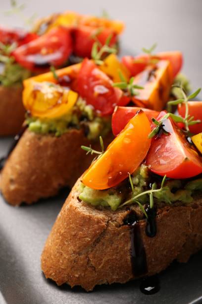 istock Delicious bruschettas with avocado, tomatoes and balsamic vinegar on gray plate, closeup 1920866919