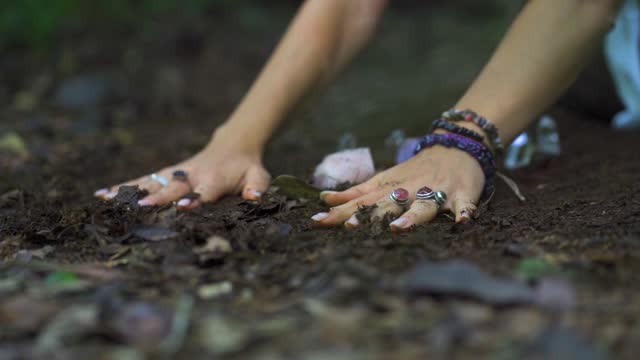 Close-up view of a person's hands rubbing the ground and meditating with a crystal stone on the riverbank in the Salto Encantado park located in Misiones, Argentina. Flora and Fauna Conservation Area.