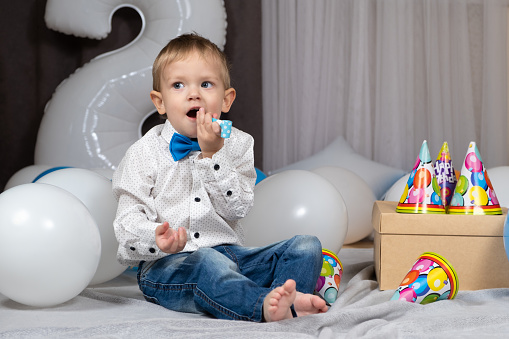 A two-year-old boy blows a pipe on his birthday.