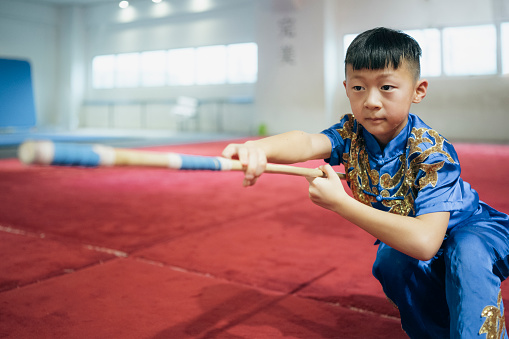 Young chinese boy practising Wushu in a gym