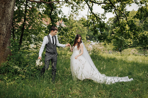 Happy young couple. The groom takes her by the hand and leads her upstairs. Wedding bouquet. Spring wedding