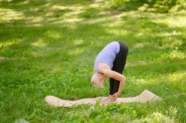 istock A middle-aged woman practices yoga outdoors, in the Standing Forward Bend pose. Uttanasana. 1920913366