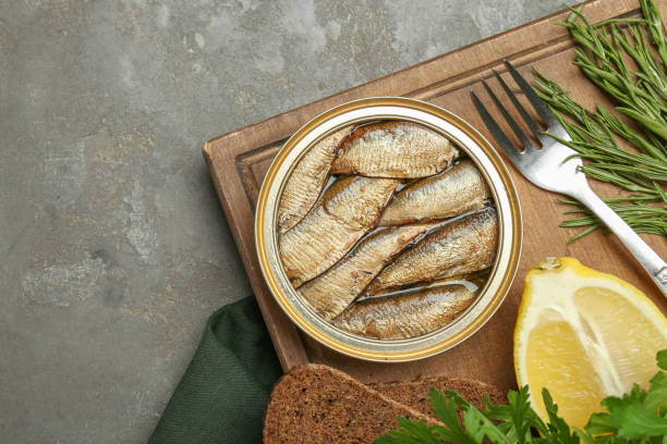istock Tin can with tasty sprats served on grey textured table, flat lay. Space for text 1920915998