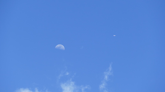Plane almost crossing moon on a blue sky