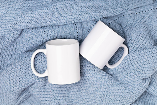 Mock up white empty mug, cup for your design and logo closeup blue sweater, blanket. Template blank for promotional text message or promotional content