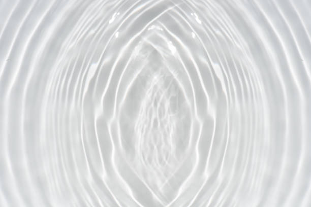 White water with ripples on the surface. Defocus blurred transparent white colored clear calm water surface texture with splashes and bubbles. Water waves with shining pattern texture background.