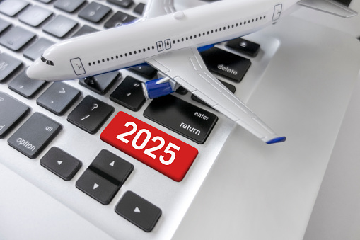 Miniature plane on a laptop with 2025 enter key symbolizing online ticketing