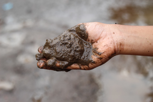 boy's hands playing in wet mud in nature