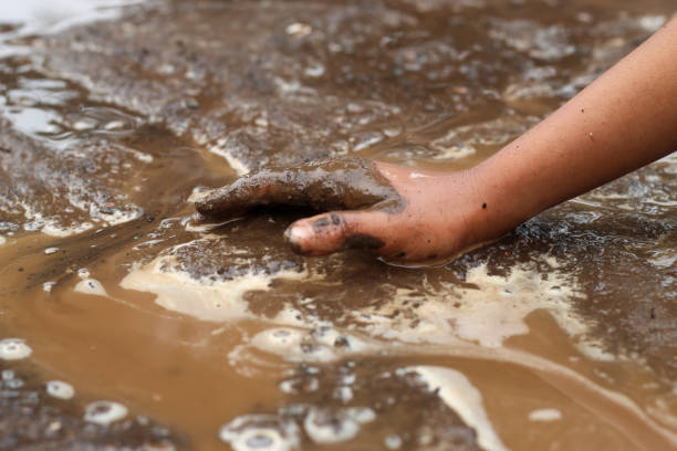 istock boy's hands playing in wet mud in nature 1920949883