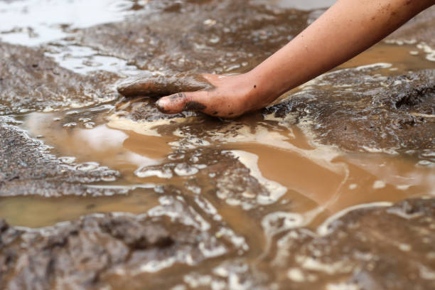 istock boy's hands playing in wet mud in nature 1920949890