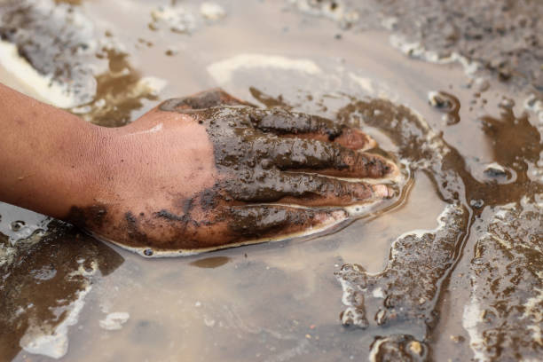 istock boy's hands playing in wet mud in nature 1920949896