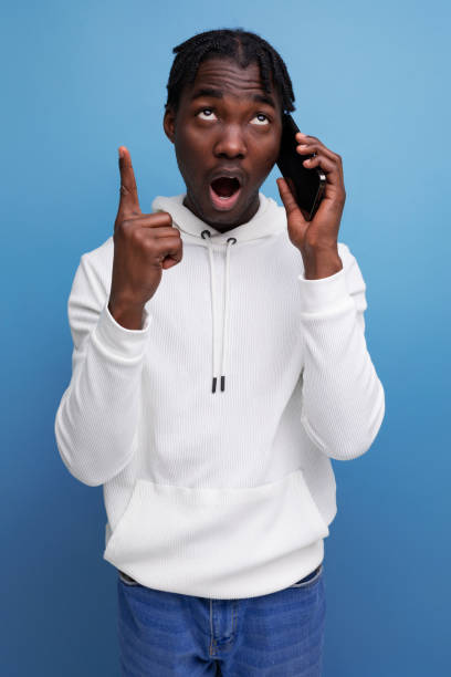 istock smart young african guy in a white sweatshirt communicates on a mobile phone 1920965841