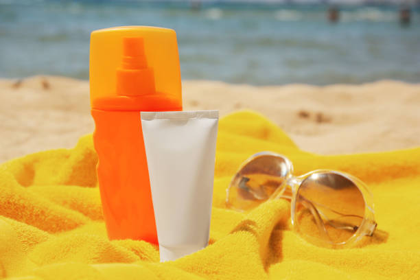 istock Sunscreen, sunglasses and towel on sandy beach. Sun protection care 1920966930