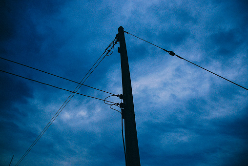 electric poles and cables that are intricate but aesthetically pleasing against the backdrop of a cloudy sky