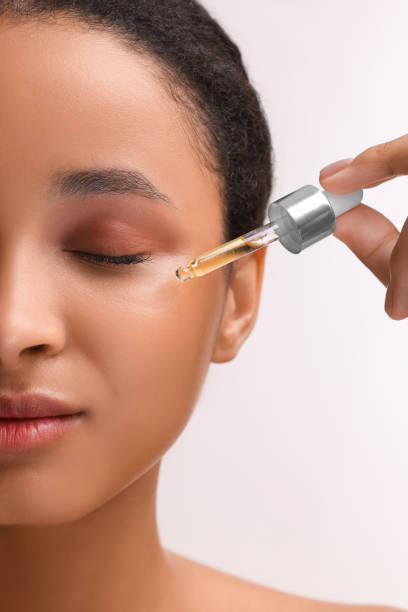 istock Woman applying serum onto her face on white background, closeup 1921007434
