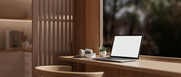 istock A white-screen laptop mockup on a wooden table against the window in a modern, comfortable room. 1921015802