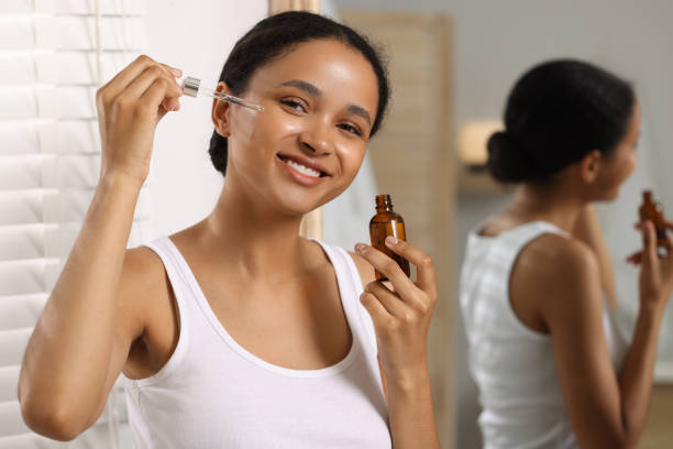 istock Smiling woman applying serum onto her face in bathroom 1921022600