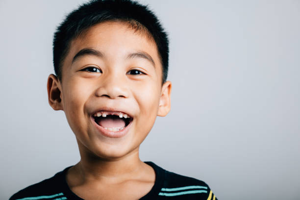 istock Boy smiling wide showing gap from lost upper tooth. Child dental development isolated on white. Joyful tooth loss growth change. Children show teeth new gap, dentist problems 1921051799