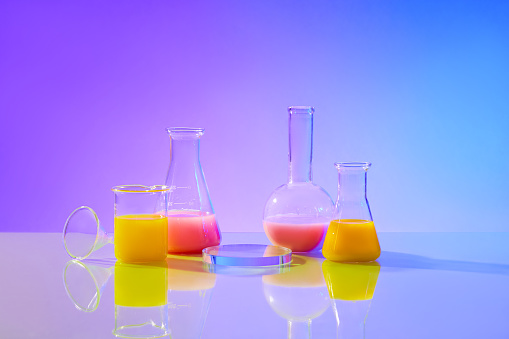 The pink and yellow liquids were stored in laboratory beakers, Erlenmeyer flasks and high-necked spherical flasks. In the middle is a circular glass podium on a blue-purple gradient background.