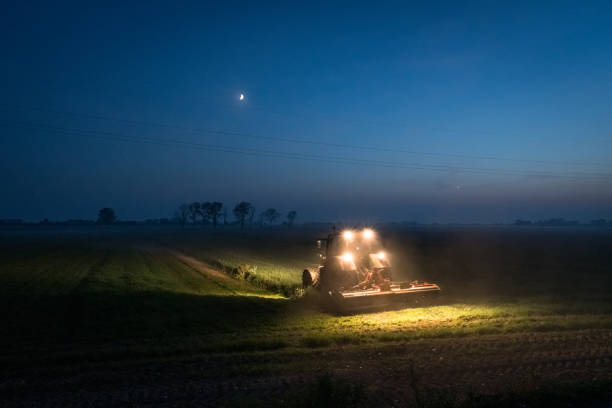 Evening with a tractor in a field with a crescent moon in Moranzani, Veneto, Italy