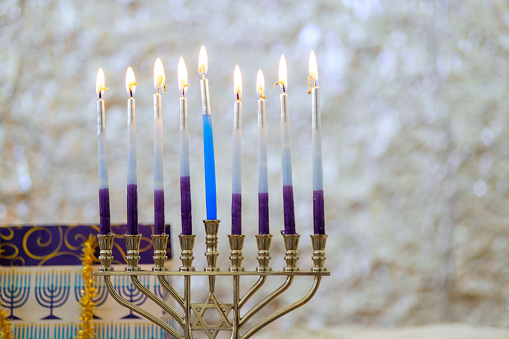 Hanukkiah Menorah candle is lit during traditional celebration of Hanukkah symbolizes Jewish faith.