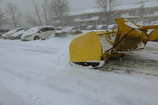 Snow is removed from parking lot by snowplow truck during heavy snowfall