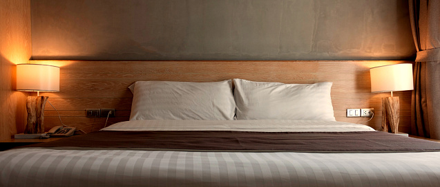 two white pillows on bed with lamp light at night in bedroom