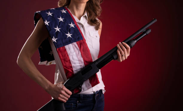 istock Armed citizen holding a shotgun with an American flag over her shoulder 1921180418