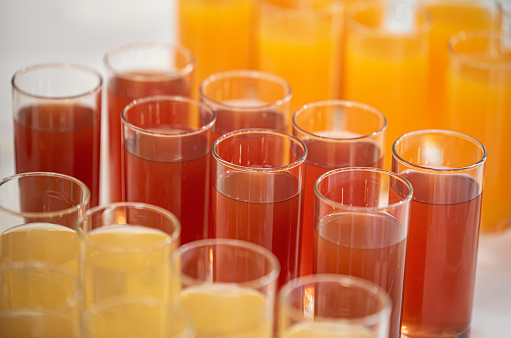 Drinking glasses with various fruit juices are available for guests at the event.