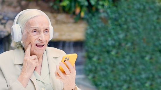 Senior woman disagreeing with the music she is listening on her mobile phone