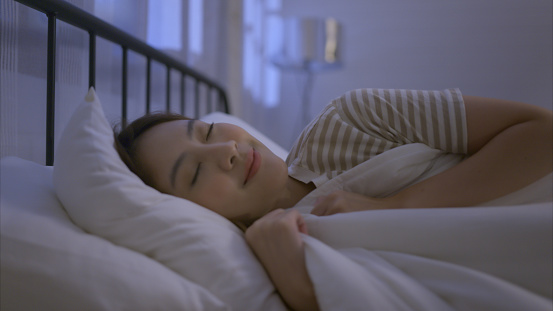 Asian young woman turn off the bedside light and then her sleep on a soft pillow