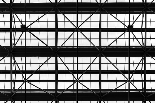 Black pattern from low angle view of silhouette roof truss structure and white transparent tiled or milk glass in green house construction. Background for environment or energy saving concept.