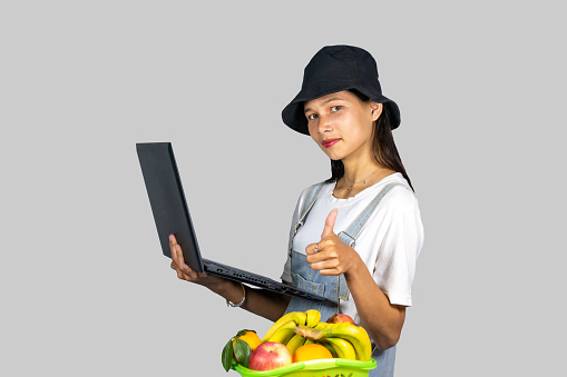 A farmer entrepreneur girl with fruits and vegetables using technology laptop and giving expressions and gestures
