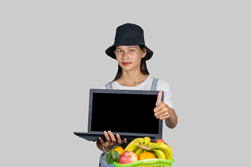 A farmer entrepreneur girl with fruits and vegetables using technology laptop and giving expressions and gestures