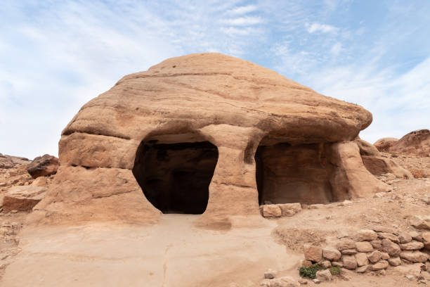 une grande grotte artificielle au début de la route touristique vers la capitale du royaume nabatéen de petra dans la ville de wadi musa en jordanie - petra ancient civilization jordan cave photos et images de collection