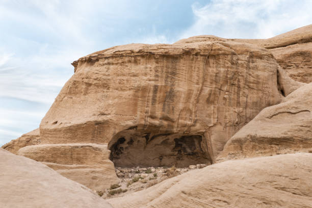 une grande grotte artificielle au début de la route touristique vers la capitale du royaume nabatéen de petra dans la ville de wadi musa en jordanie - petra ancient civilization jordan cave photos et images de collection