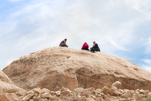 Wadi Musa, Jordan, October 05, 2023 : A Bedouin family sits on top of a hill on a tourist route in the Nabatean capital of Petra in Wadi Musa city in Jordan