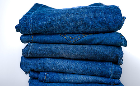 Blue jeans pants folded lie on a pile on a white background close up isolated