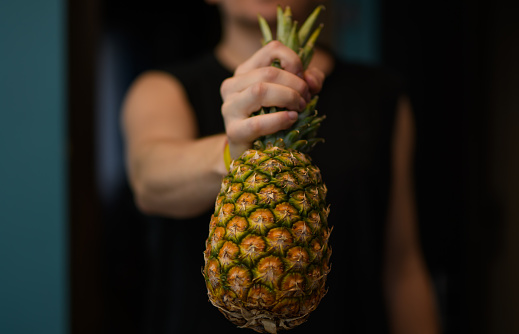 A man holds a ripe pineapple in his hand close up isolated