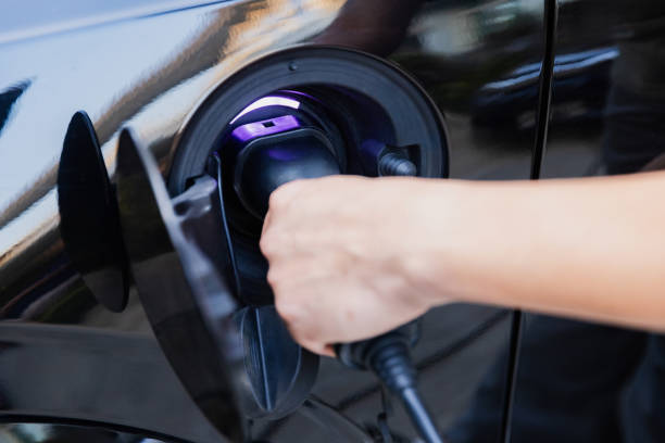 istock Man teaching woman how to charge electric car. 1921484132