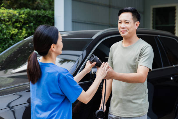 istock Man teaching woman how to charge electric car. 1921484385