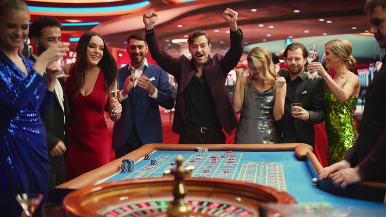 Casino Players Making Bets at a Roulette Table. Vibrant Crowd of International People Enjoying Nightlife in a City. Gamblers Excited About Successful Bets and Winning a Big Sum of Money. Slow Motion.