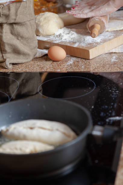 Women hands roll out dough in frying pan foreground