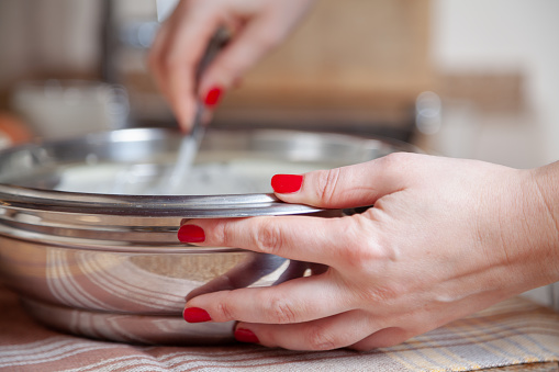 Well-groomed female hand holding a metal bowl close-up