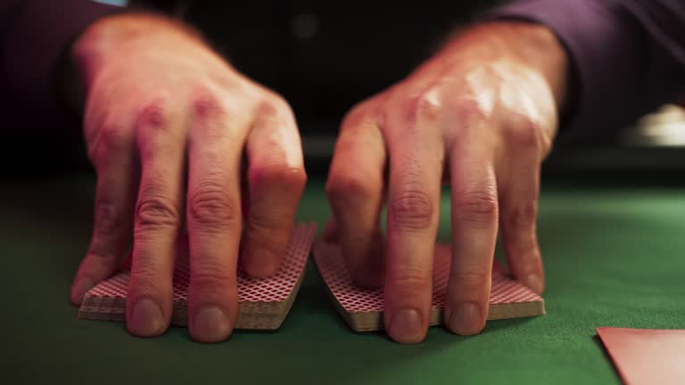 Close Up On Hands Of Professional Poker Dealer Doing A Riffle Shuffle Of Playing Cards Before High Stakes Game In Luxurious Casino. Anonymous Croupier Shuffling Deck Before Poker Tournament.