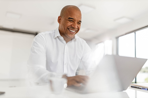 Happy black businessman working on a computer in the office. Copy space.